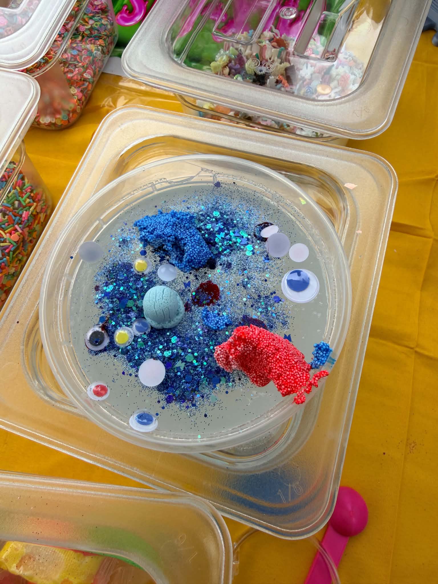 Jelly slime decorated with blue sparkle, playful eyes, and colorful additions